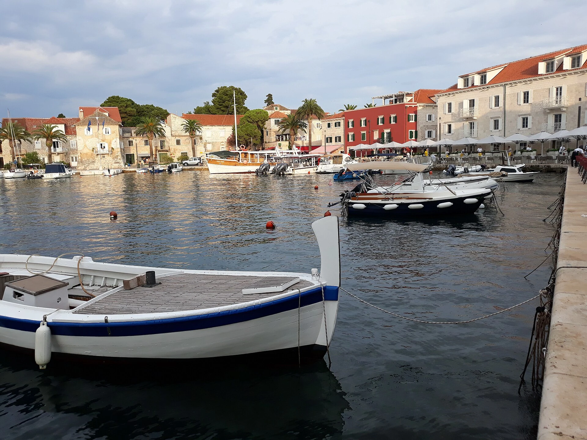 Brodice u sutivanskoj luci ispred kamenih kuća, palmi i terasa na obali